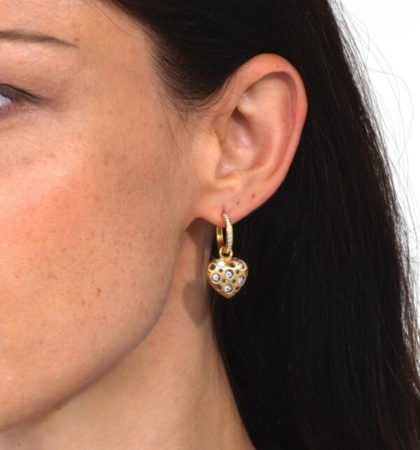 A woman wearing gold earrings with white stones.