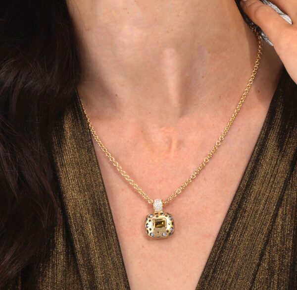 A woman wearing a necklace with a gold pendant.