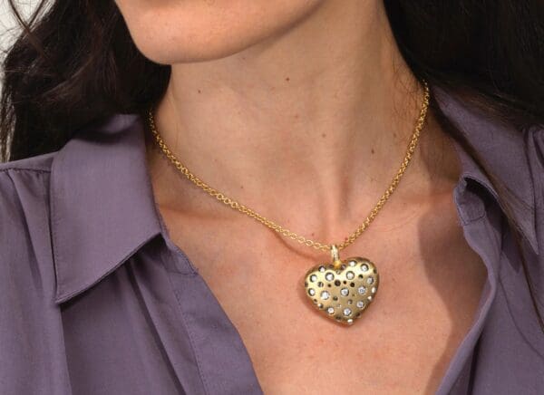 A woman wearing a gold heart shaped necklace.