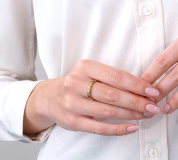 A woman wearing a white shirt and gold ring.