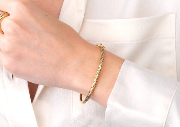 A woman wearing a white shirt and gold bracelet.