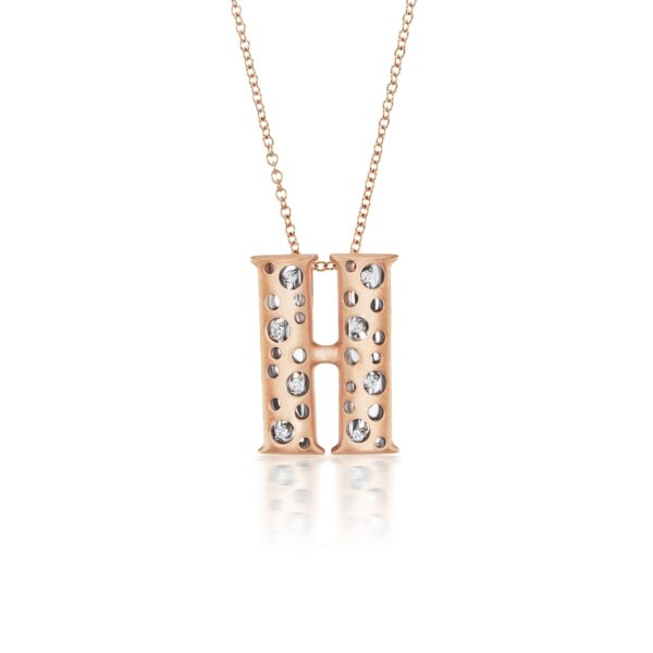 A rose gold necklace with two letters and diamonds.