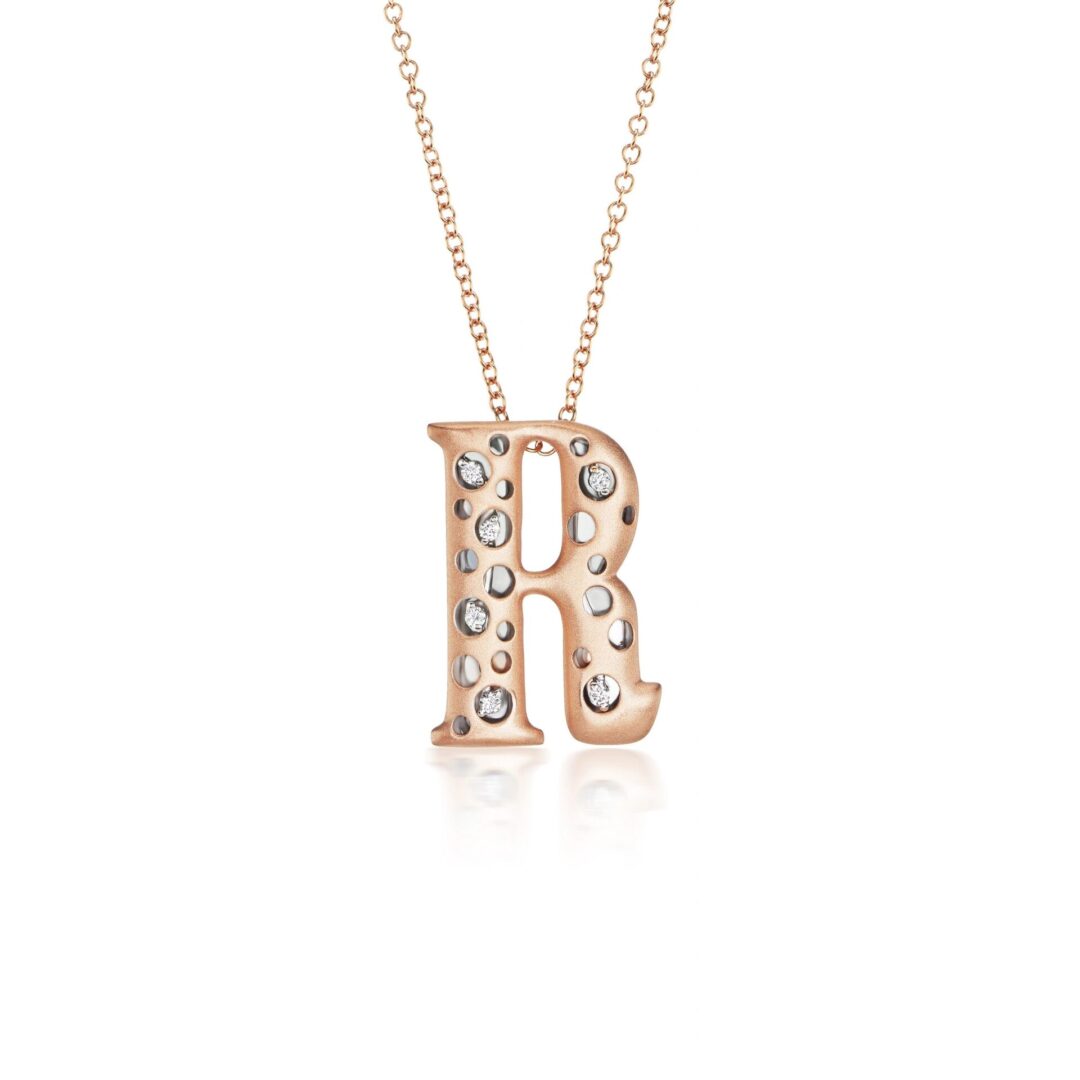 A rose gold necklace with the letter r