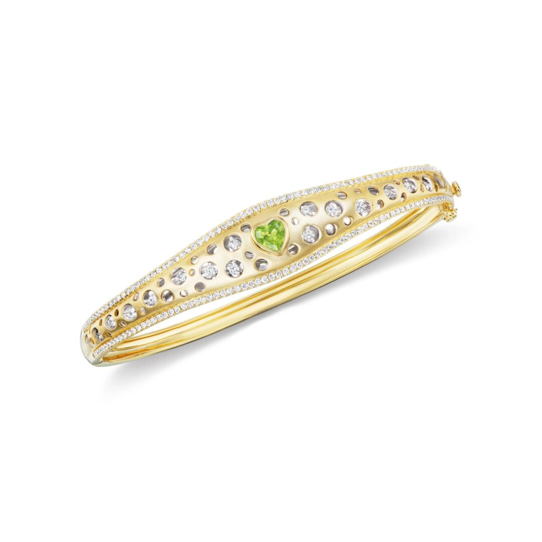 A gold bangle with green and white stones.