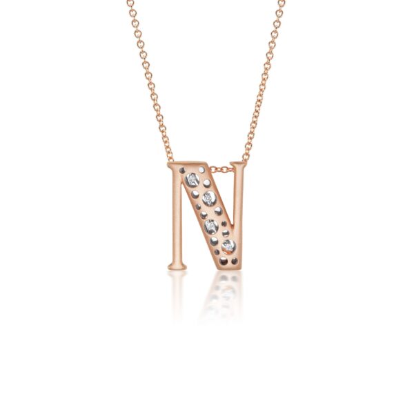 A rose gold necklace with an n letter