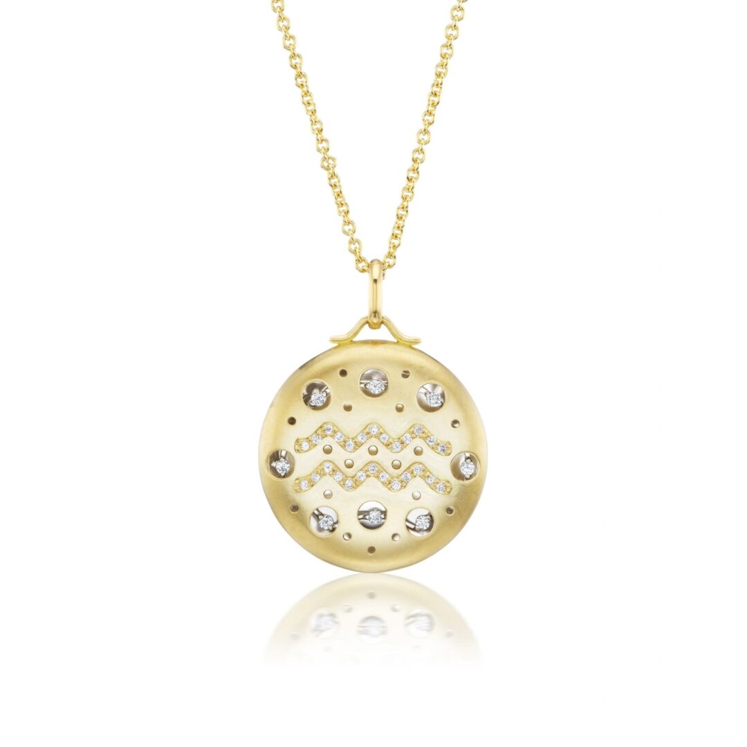 A gold necklace with a round pendant and some small diamonds