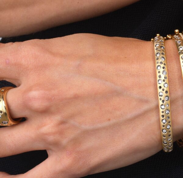 A woman 's hand with two bracelets and one ring.