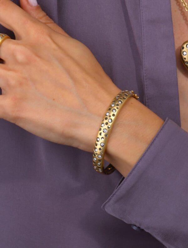 A woman wearing a gold bracelet and ring.