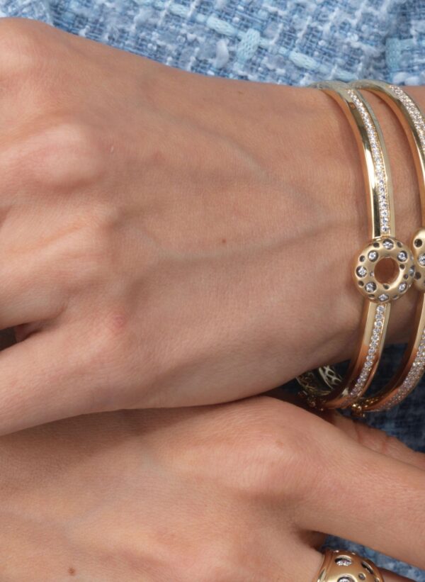 A woman 's hands with three bracelets on her wrist.