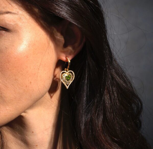 A woman wearing earrings with green stones.