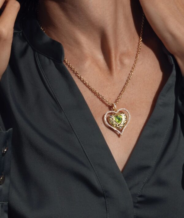 A woman wearing a necklace with a heart shaped pendant.