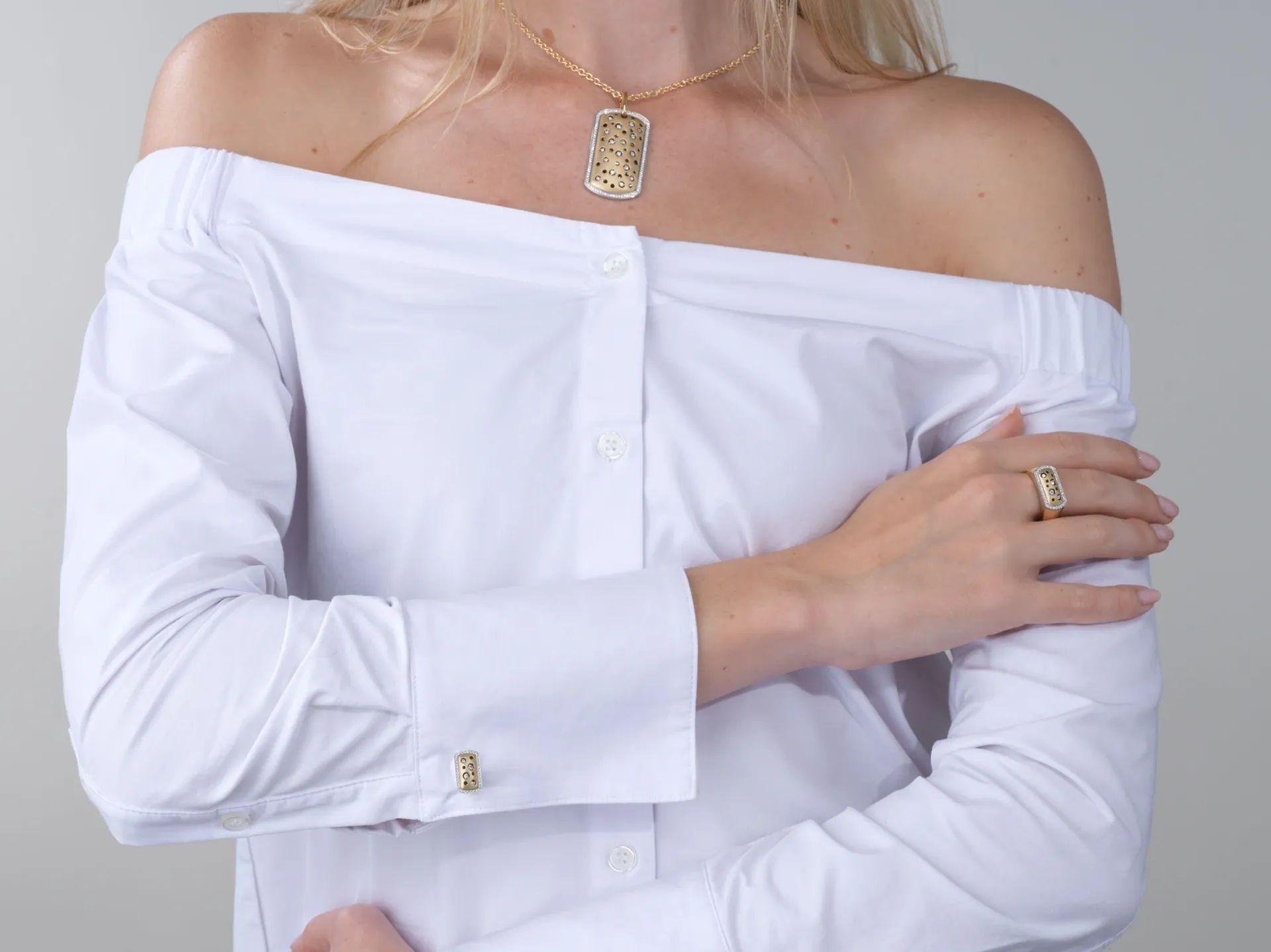 A woman wearing white shirt and gold jewelry.