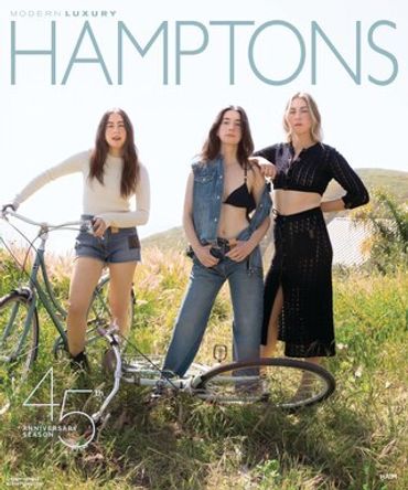 Three women posing with a bike in the grass.