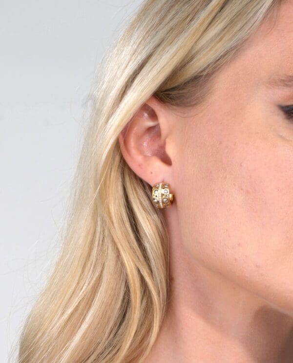 A woman wearing gold earrings and a white background